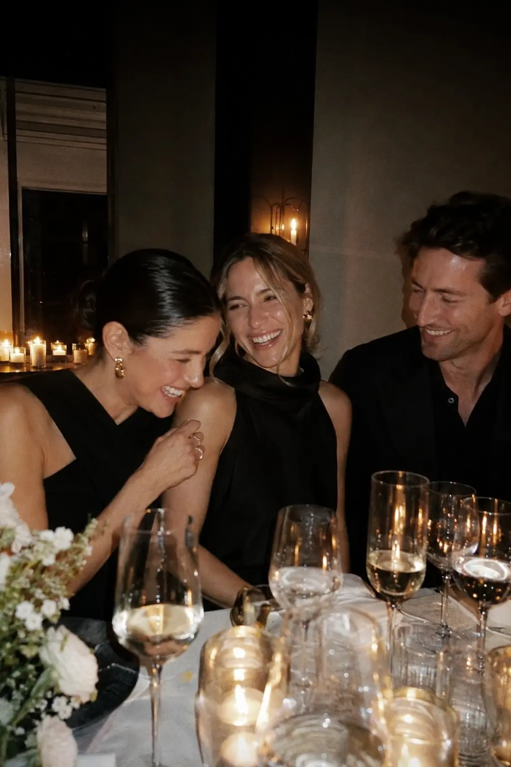 Three friends laughing over dinner