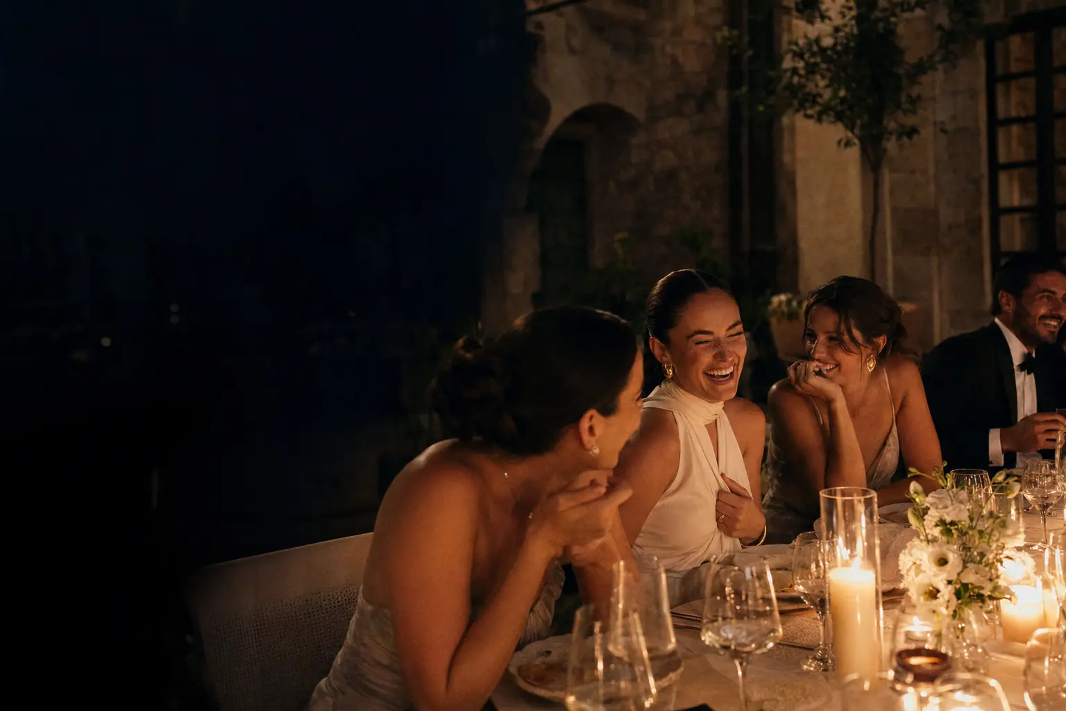 Friends laughing together at a candlelit dinner